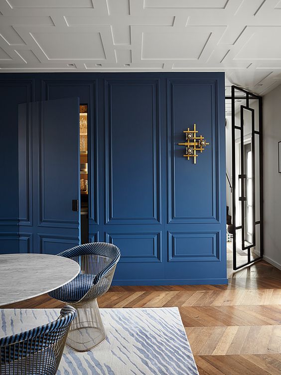 Blue Panel Hidden Door Interiors - 17 That Will Make You Fall in Love With Panelled Walls: A storage area in a dining area is made a stand out feature by using a panel design for the walls and painted in a deep blue integrating a hidden panel door for access to the storage area. @chloedominik #panelhiddendoor #panelledwalls #panelwalls #panelledinteriors #panelledinteriorwalls #panelwallideas #panelwalldesigns #hiddendoorsinwallpanel #panelwalldiningroom #bluepanelledwalls