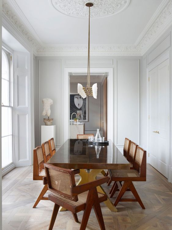 Modern Dining Room - 17 Interiors That Will Make You Fall in Love With Panelled Walls: a beautiful modern dining room is designed with traditional white panel walls, ceiling moulding and parquet floorings. The modern dining area furniture contrasts the surroundings to make it a balanced and interesting dining space. @chloedominik 
#panelledwalls #panelwalls #panelledinteriors #panelledinteriorwalls #panelwallideas #panelwalldesigns #panelledwalldiningroom #panelledwalldining