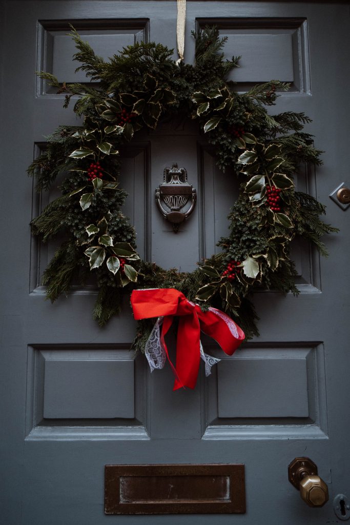 Traditional Holly Wreath: 9 Beautiful Christmas Flowers & Plants To Decorate With: A beautiful traditional evergreen Christmas holly wreath for the front door with a red ribbon to finish off the wreath. #christmaswreaths #christmaswreathsforfrontdoor #traditionalchristmaswreaths #traditionalchristmaswreathsevergreen #hollywreath