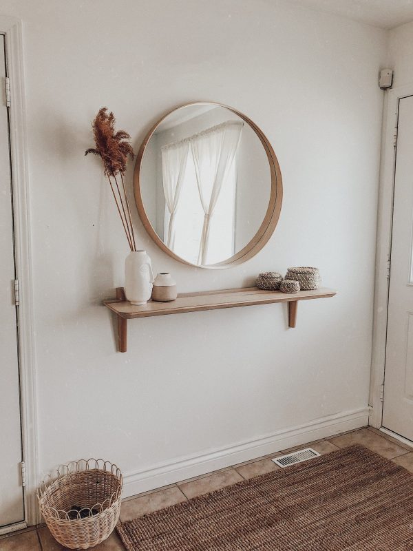 Minimal Hallway Decor - 7 Great Tips To Organize & Style Your Hallway: A hallway entrance with a small space makes the most use by having minimal decor placed on the wall like this wooden mirror and single shelf combo. Interior unknown. #hallwaydesign #hallwaydecor #hallwayideas #minimalhallway #minimalhallwaydecor #minimalhallwaydecorentrance